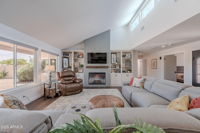 living room with high vaulted ceiling, a glass covered fireplace, plenty of natural light, and wood finished floors