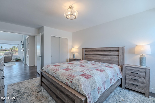 bedroom featuring baseboards, a chandelier, wood finished floors, and a closet
