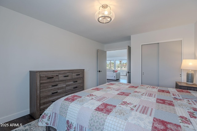 bedroom with a closet, dark wood-style flooring, and baseboards