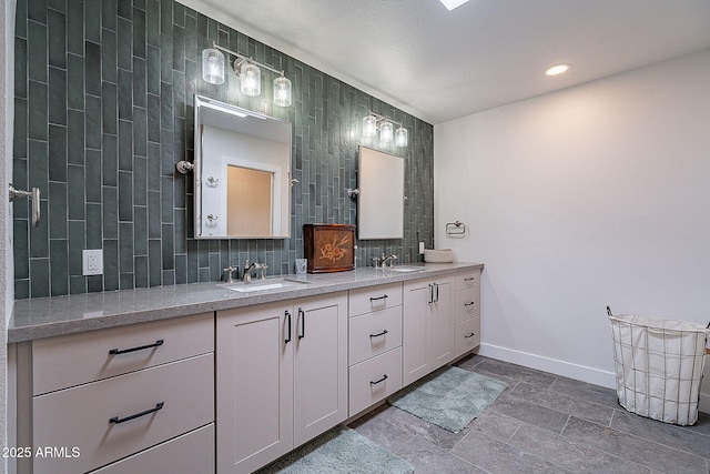 bathroom featuring baseboards, a sink, decorative backsplash, and double vanity