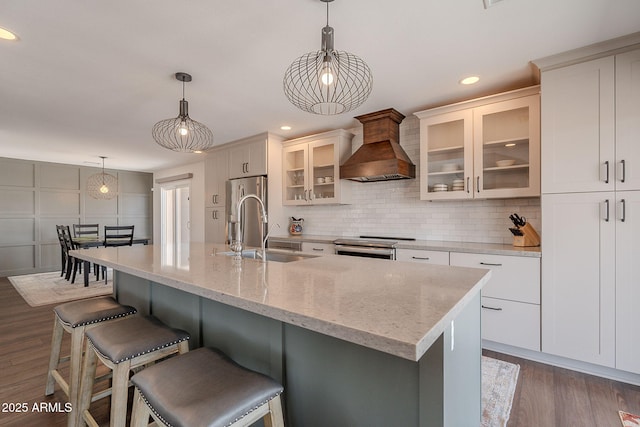 kitchen with premium range hood, dark wood-style floors, white cabinetry, tasteful backsplash, and a sink