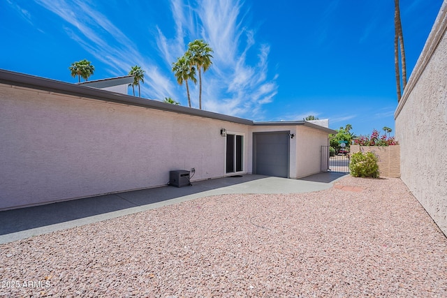 rear view of house with a gate, a patio area, stucco siding, and fence