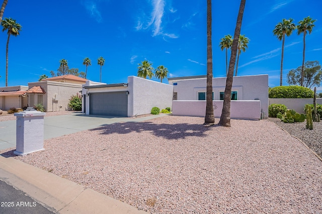 view of front facade with concrete driveway, an attached garage, fence, and stucco siding