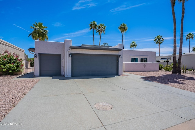 view of front facade featuring fence, an attached garage, driveway, and stucco siding