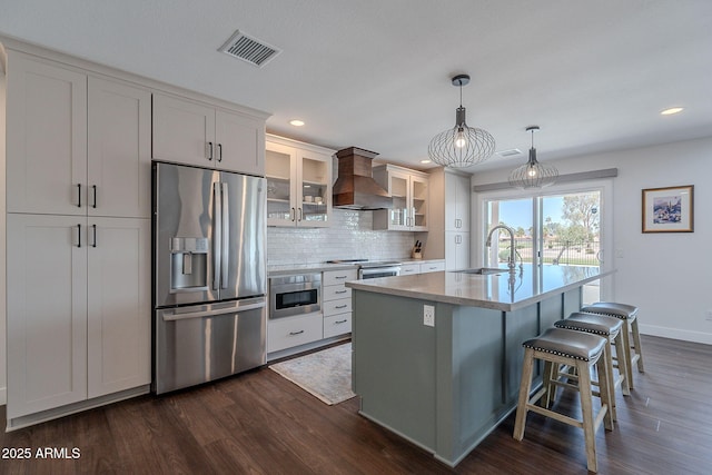 kitchen featuring wall chimney range hood, appliances with stainless steel finishes, dark wood finished floors, and visible vents