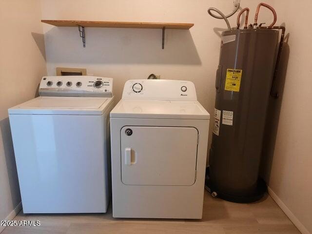 clothes washing area with laundry area, light wood finished floors, baseboards, washer and clothes dryer, and water heater