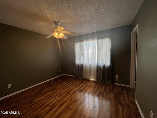 spare room with ceiling fan, a textured ceiling, baseboards, and dark wood-style flooring