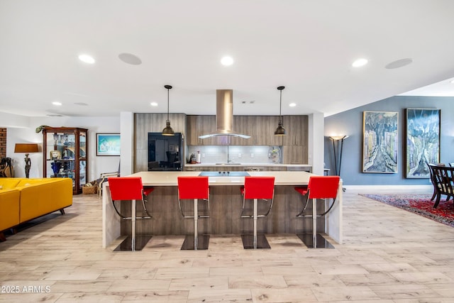 kitchen featuring pendant lighting, island range hood, and a breakfast bar area