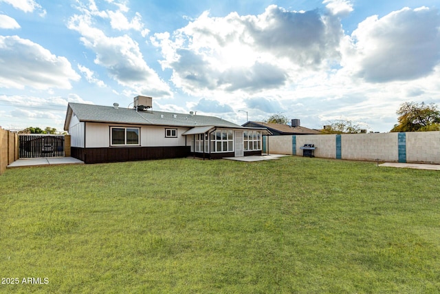 rear view of property with a sunroom, a patio, and a lawn