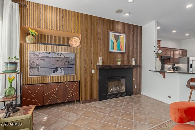 living room featuring wooden walls, a fireplace, and light tile patterned flooring