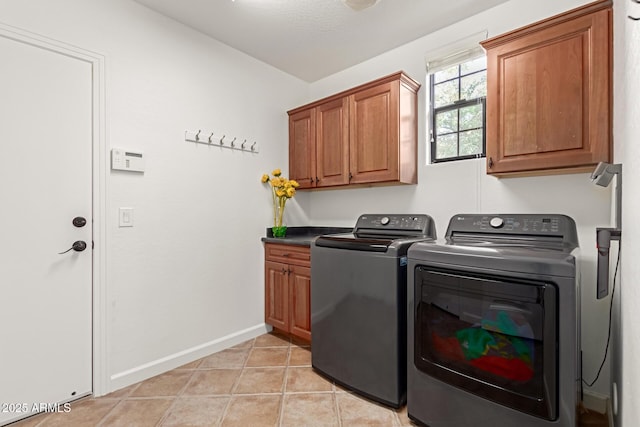 clothes washing area featuring cabinets, light tile patterned floors, and washer and dryer