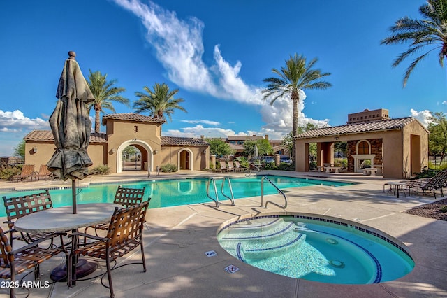 view of pool featuring a community hot tub, a patio, and exterior fireplace