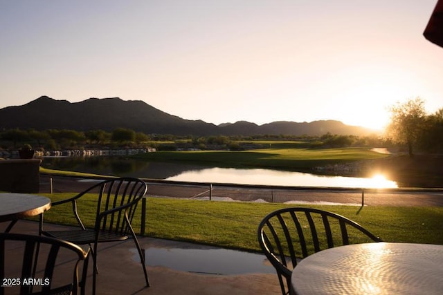 patio terrace at dusk featuring a yard and a water and mountain view