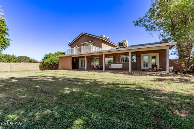 back of house featuring a balcony, french doors, cooling unit, and a lawn