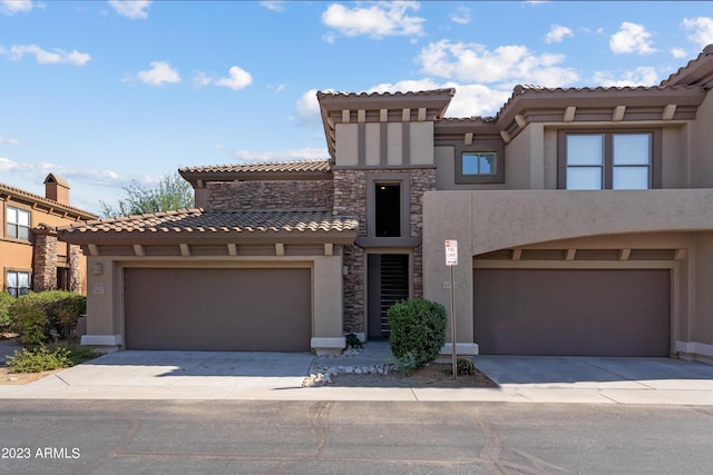 view of front facade with stone siding, an attached garage, driveway, and stucco siding