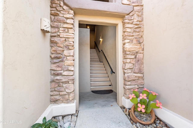 entrance to property featuring stone siding and stucco siding