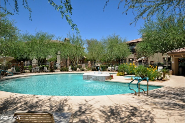 community pool with a patio area and fence