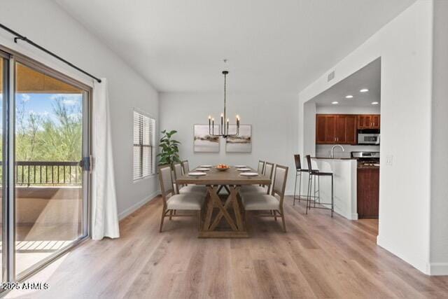 dining area featuring baseboards, light wood finished floors, visible vents, and an inviting chandelier