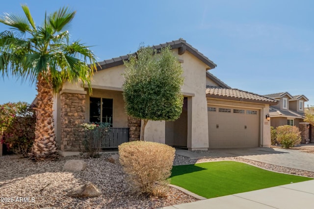 view of front of home with decorative driveway, an attached garage, a tile roof, and stucco siding