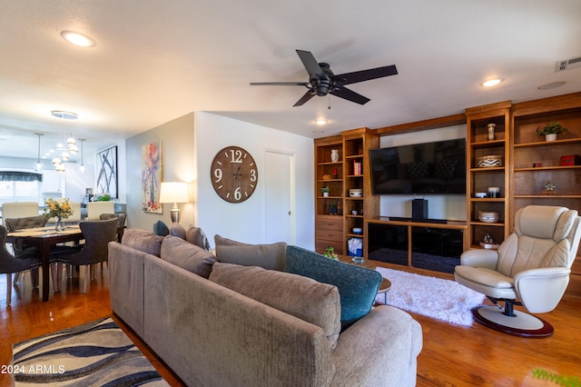 living room with ceiling fan with notable chandelier and wood-type flooring