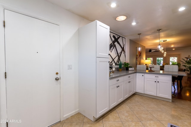 kitchen featuring ceiling fan, pendant lighting, kitchen peninsula, light tile patterned floors, and white cabinetry