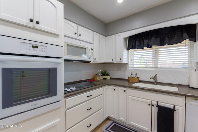 kitchen featuring tasteful backsplash, white appliances, dark stone counters, sink, and white cabinets