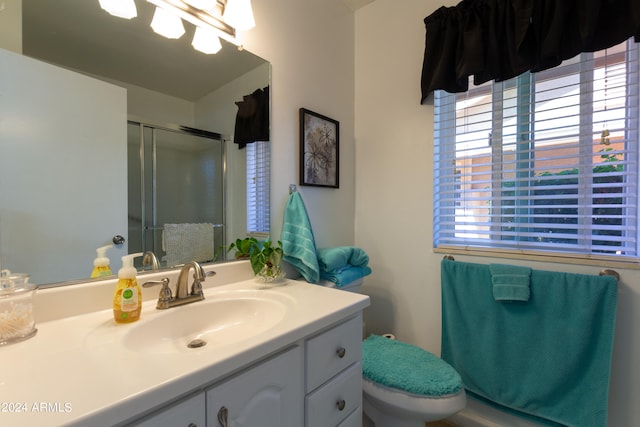 bathroom with plenty of natural light, a shower with shower door, vanity, and toilet