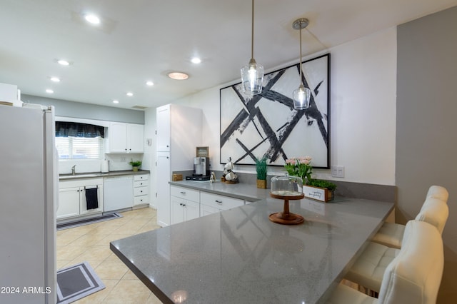 kitchen with white cabinets, white appliances, sink, kitchen peninsula, and pendant lighting