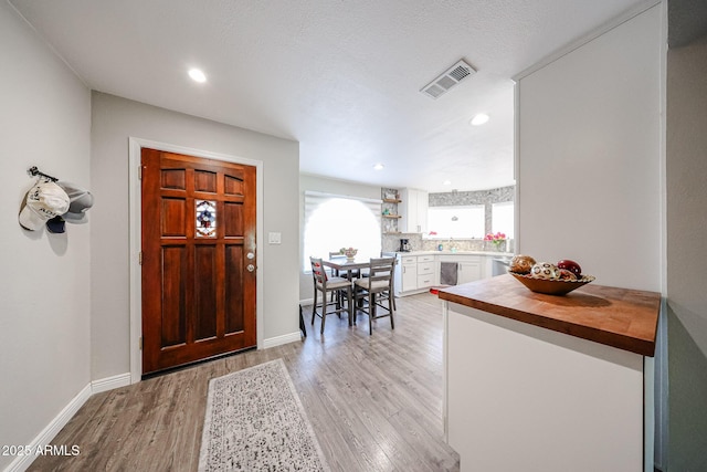 entryway with sink, a textured ceiling, and light wood-type flooring