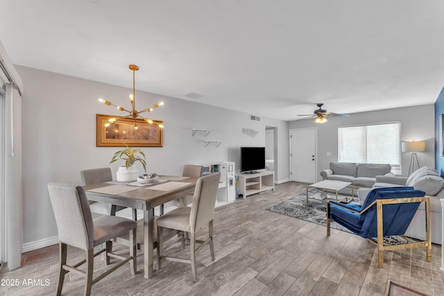 dining area with ceiling fan with notable chandelier, light wood-style floors, visible vents, and baseboards