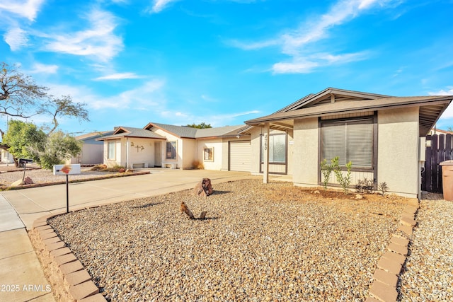 ranch-style home with an attached garage, fence, driveway, and stucco siding