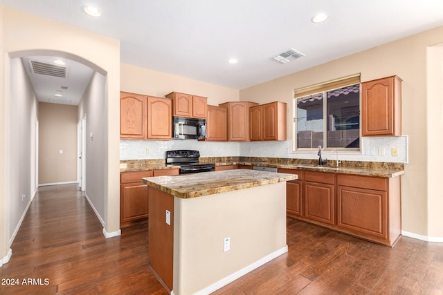 kitchen featuring sink, black appliances, light stone counters, a kitchen island, and dark wood-type flooring