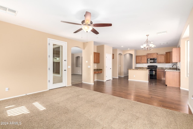 unfurnished living room featuring ceiling fan with notable chandelier, dark wood-type flooring, and sink