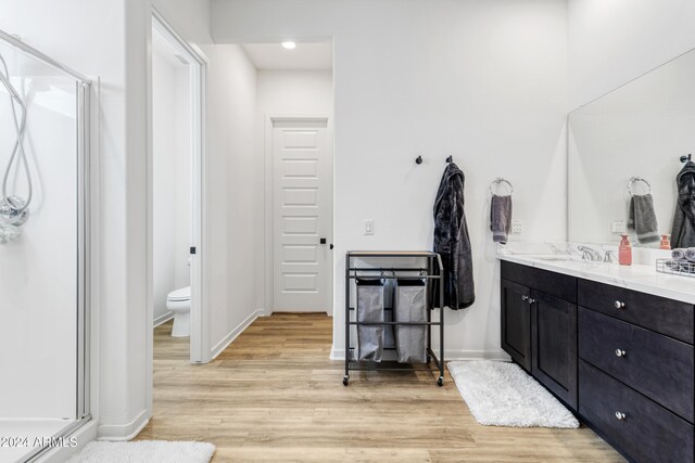 bathroom featuring toilet, an enclosed shower, hardwood / wood-style flooring, and vanity