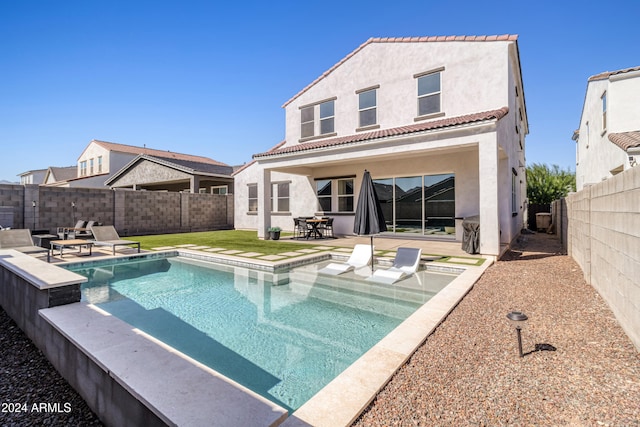 back of property featuring a fenced in pool and a patio