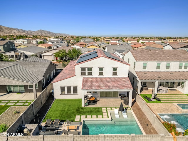 back of property with a lawn, a mountain view, a patio, and a fenced in pool