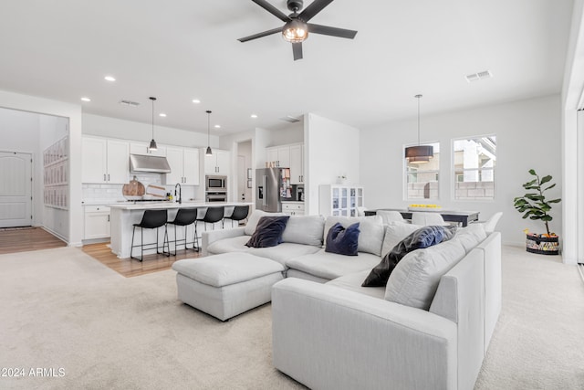 living room featuring sink, light hardwood / wood-style floors, and ceiling fan