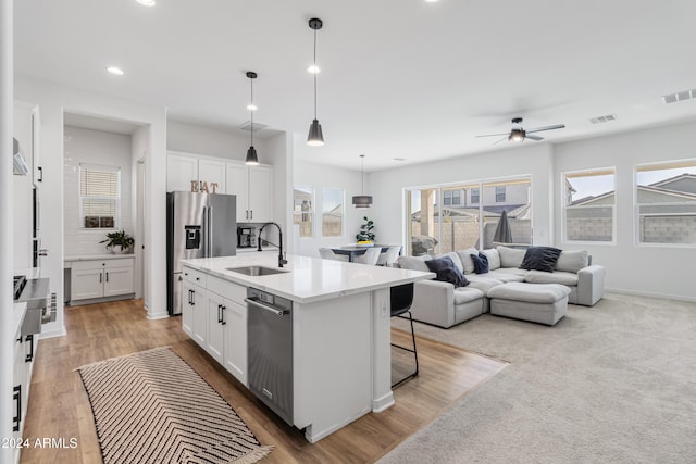 kitchen featuring stainless steel appliances, sink, an island with sink, and white cabinets