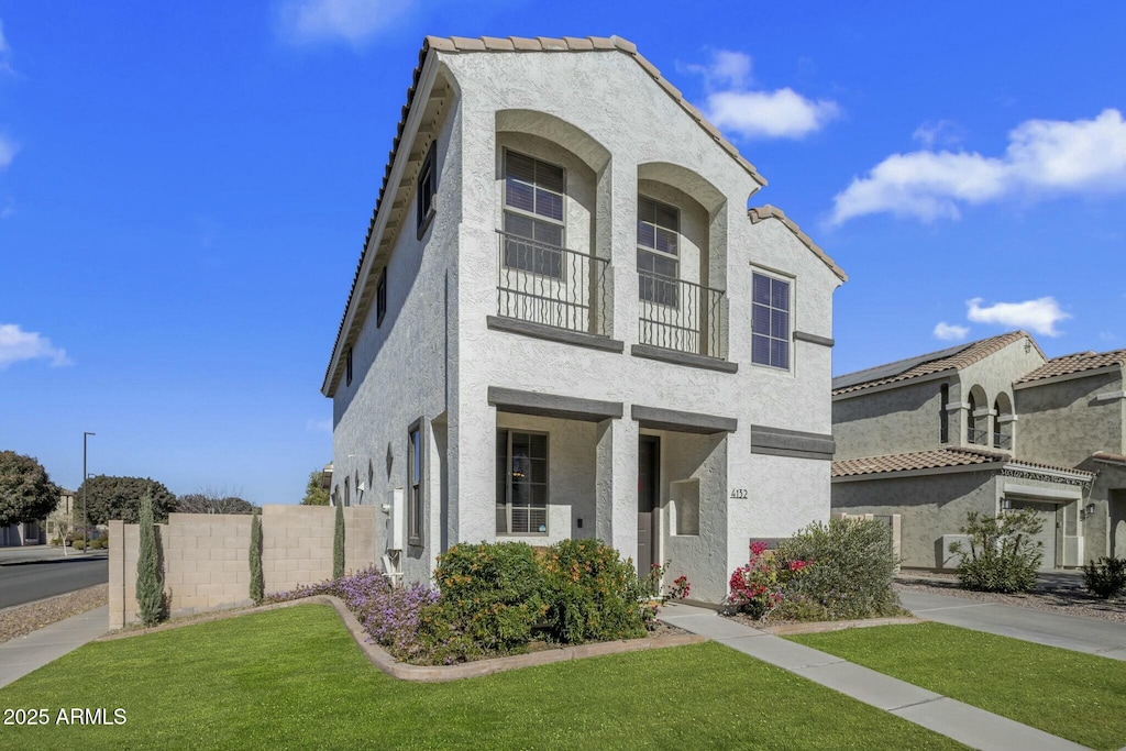 view of front of home featuring stucco siding, a front yard, and fence