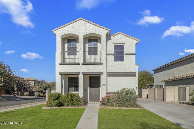 view of front of property with stucco siding, a tile roof, a front lawn, and fence