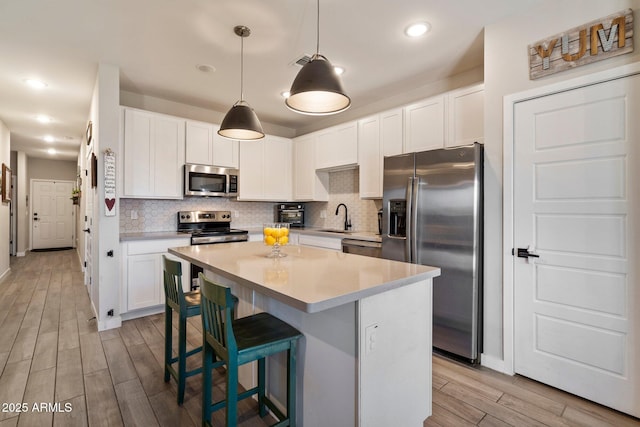 2753 E Fossil Ridge Rd, Phoenix, AZ 85050 - kitchen featuring appliances with stainless steel finishes, light wood-type flooring, a kitchen island, decorative backsplash, and recessed lighting