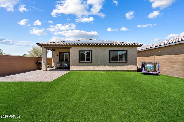 2753 E Fossil Ridge Rd, Phoenix, AZ 85050 - rear view of property with a trampoline, a patio area, roof mounted solar panels, stucco siding, and a fenced backyard