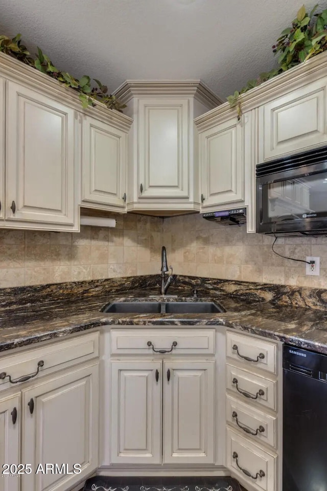 kitchen featuring dark stone countertops, backsplash, black appliances, and a sink