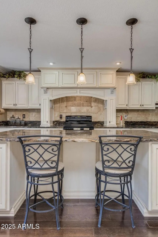 kitchen featuring dark wood finished floors, dark stone countertops, and black range with electric cooktop