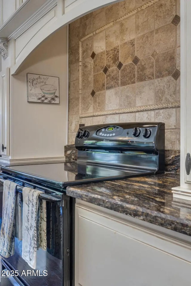 kitchen featuring electric range, white cabinets, and dark stone counters