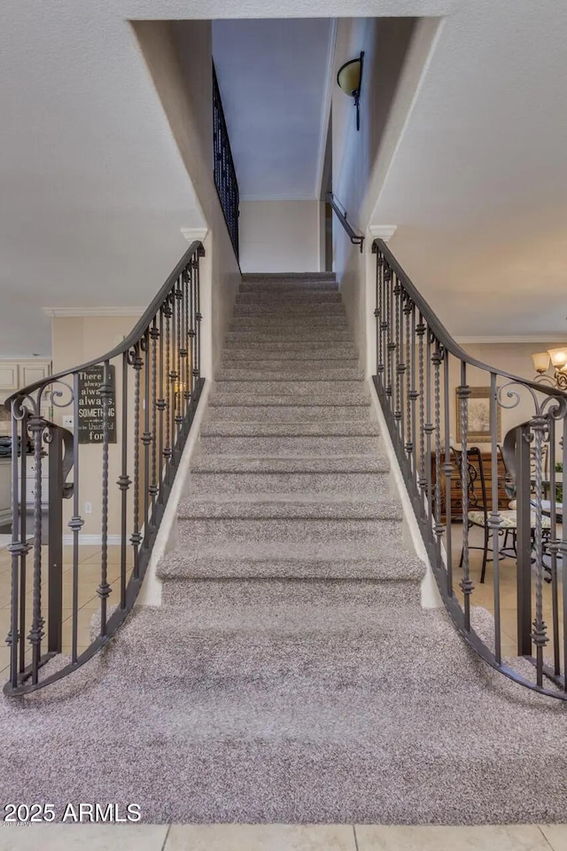 staircase with an inviting chandelier and ornamental molding