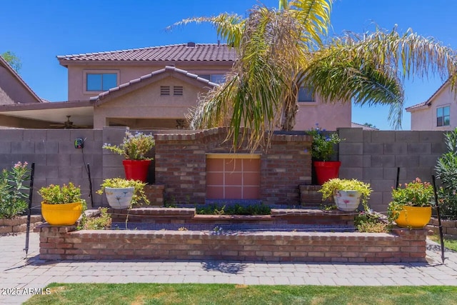 view of front facade featuring stucco siding, a tile roof, and fence