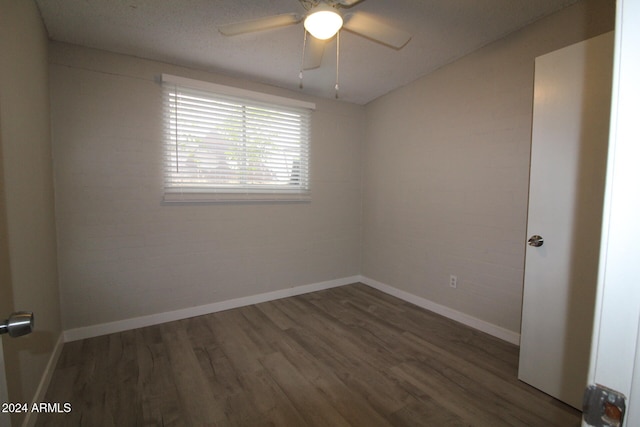 empty room featuring dark hardwood / wood-style floors, a textured ceiling, brick wall, and ceiling fan