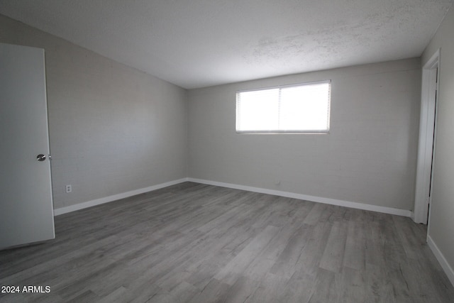 empty room with a textured ceiling and wood-type flooring