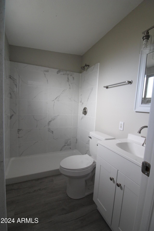 bathroom featuring vanity, a tile shower, toilet, and hardwood / wood-style floors